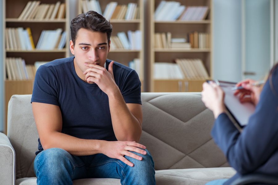 man with addiction sitting on couch for therapy