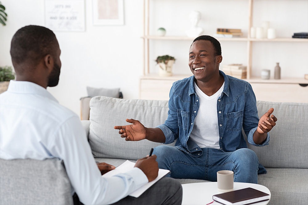 man smiiling and sitting on a couch in therapy