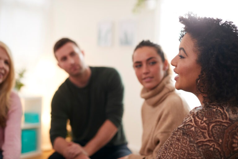 Man and two women turned to listen to speaking woman