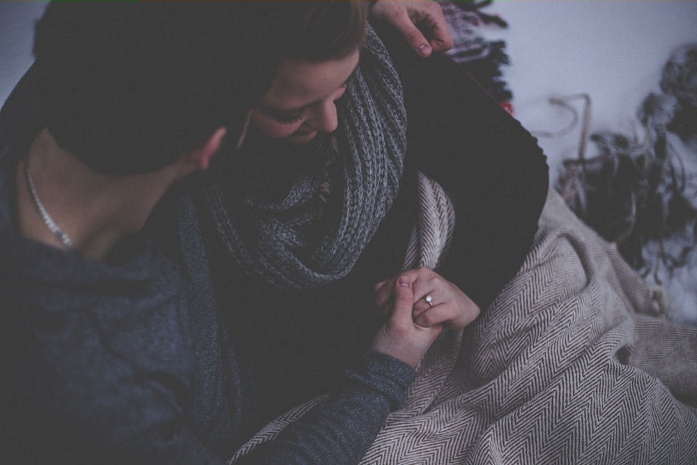 Man under blanket with wife, comforting her through detox symptoms