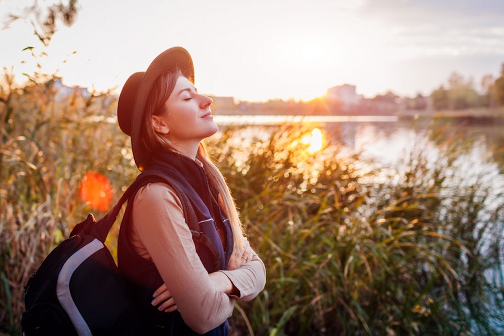 Woman closing eyes while peacefully hiking in marshland