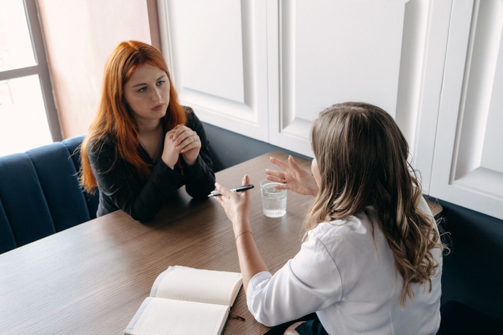 Woman explaining effects of cocaine across the table from a young woman