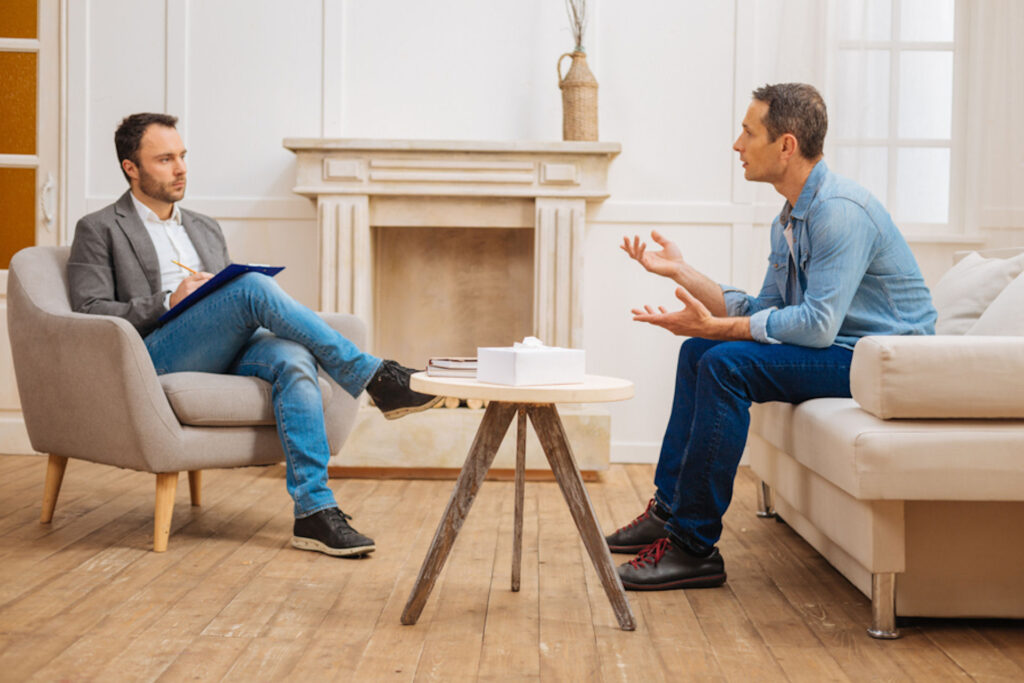 Man explaining to a therapist while each sit in couches in office