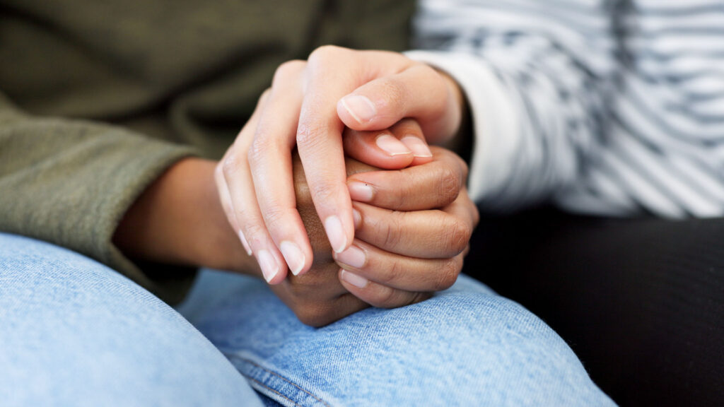 Addicted person's hands covered by a supportive person's hand