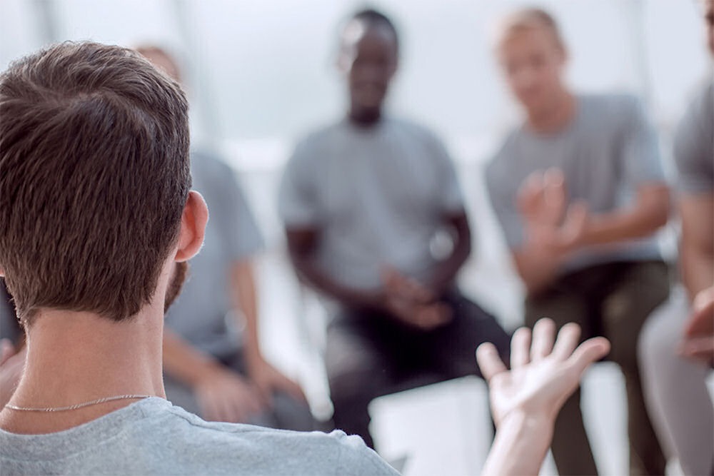 Man explaining street names for opioids to men in opioid addiction group therapy