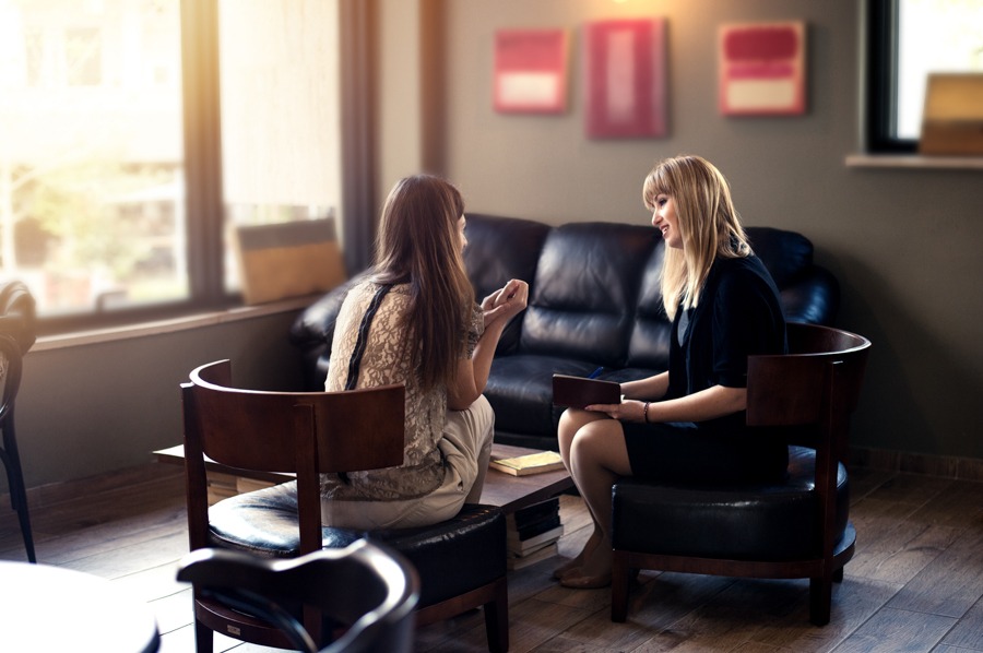 Woman talking to Borderline Personality Disorder counselor in office furnished with leather couches and leather chairs