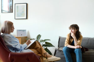 Woman sitting on a grey couch, talking to casually dressed therapist about hard drugs