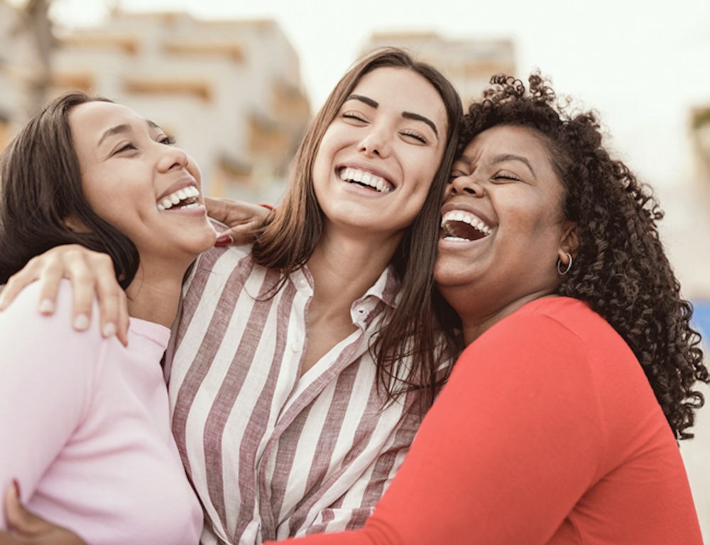 Group of three female friends laughing and hugging