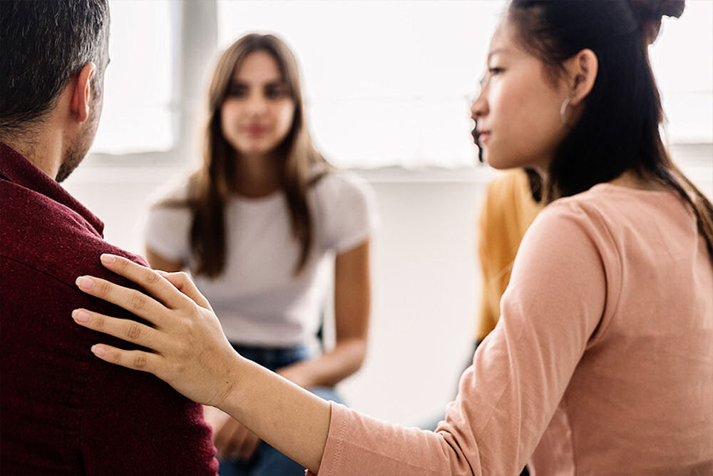 Woman reassuring person seated next to her in an OCD support group