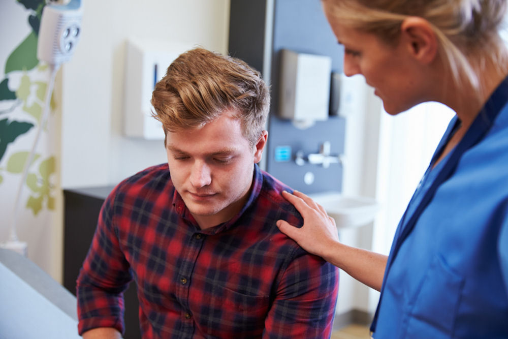 Nurse reassuring young man about cannabis addiction treatment