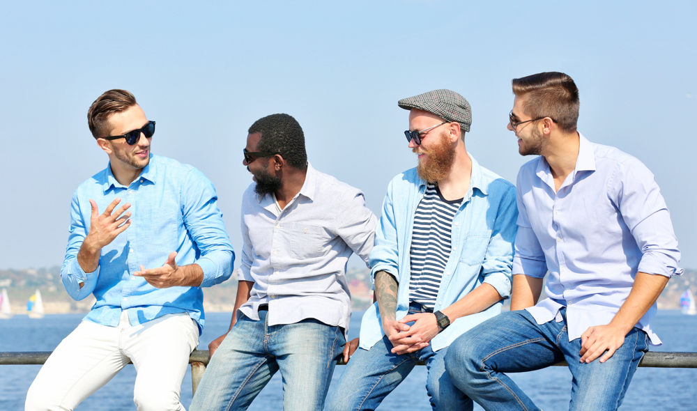 Group of four men dressed for light weather talking happily