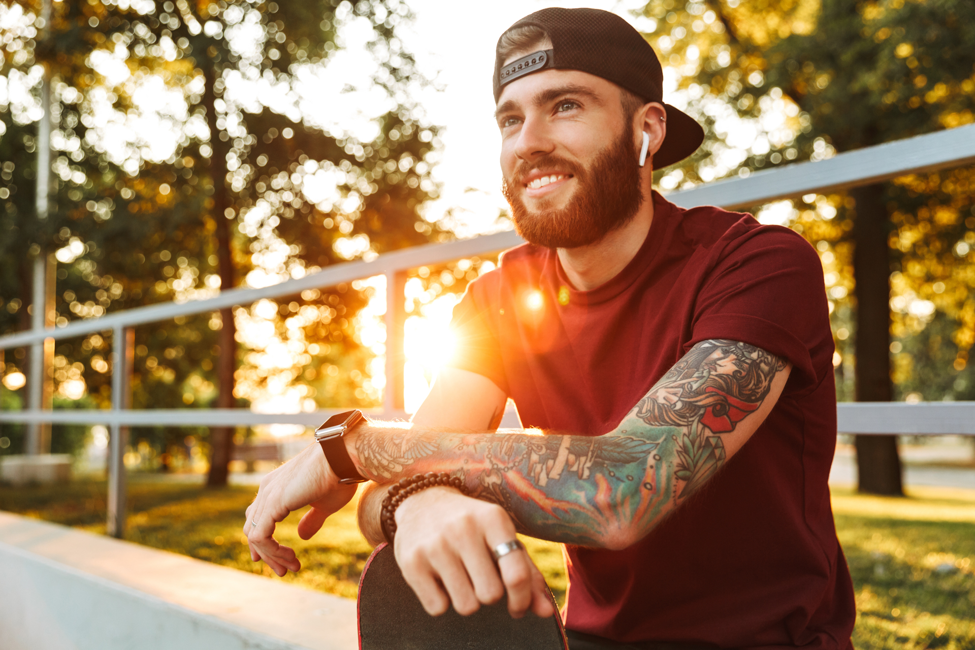 Man with tattoos listening on earbuds while relaxing on skate ramp