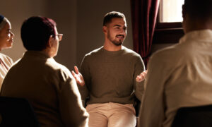 Man explaining chronic pain and addiction to members of support group